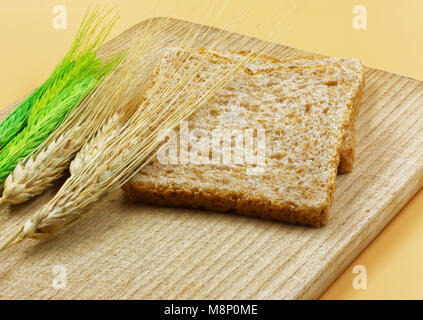 Einige Ähren, Kolben und Rispen von Getreide und Brot auf einem alten Holzplatte. Schließen horizontale Ansicht. Stockfoto