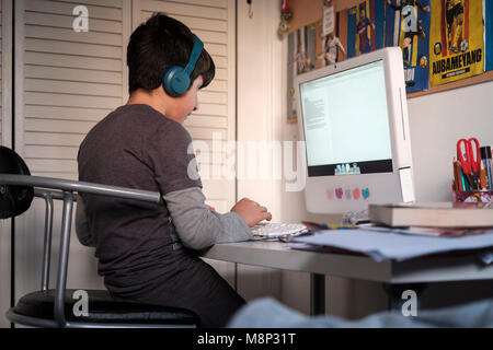 Surrey, Großbritannien. 10 Jahre alter Junge auf dem Computer in seinem Schlafzimmer - Seitenansicht
