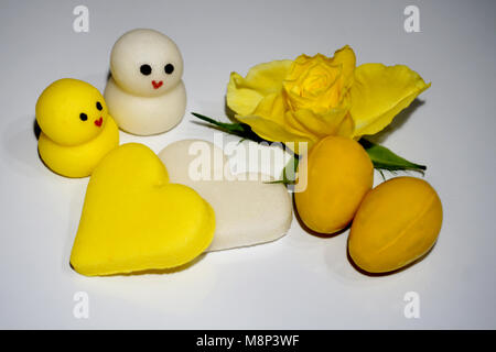 Marzipan Cookies in gelben und weißen Farben für Ostern Dekoration und gelbe rose im Hintergrund Stockfoto