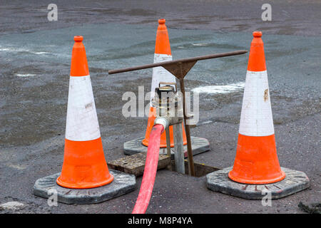 Eine hohe Sichtbarkeit Leitkegel umgebenden Wasser hydrant als Sicherheitsmaßnahme, während es in Gebrauch ist Stockfoto