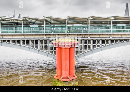 Eine der verdreifacht, rot gefärbt Säulen aus dem ursprünglichen Blackfriars Railway Bridge vor der aktuellen Eisenbahn Brücke über die Themse auf Stockfoto