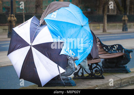 Sonnenschirme gepflasterten zusammen eine improvisierte Unterschlupf für eine obdachlose Person schlafen auf einer Bank am nördlichen Ufer der Themse, Lon Stockfoto