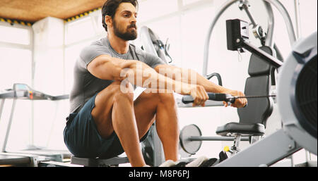 Fit Mann Schulung an Zeile Maschine im Fitness-Studio Stockfoto