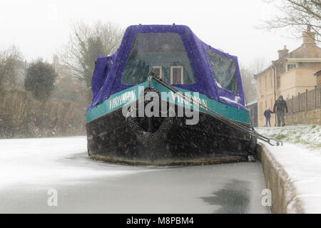 Badewanne, Großbritannien - 01 März 2018 schmalen Boot auf dem zugefrorenen Kanal in den Schnee. Winterlandschaft entlang Kennet und Avon Kanal in der Badewanne, mit Menschen zu Fuß auf verschneiten Tag Stockfoto