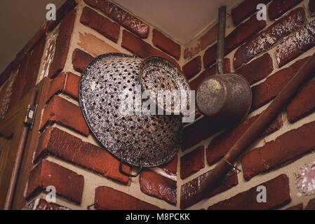 Gusseisen Pfannen und Töpfe hängen an eine Wand. Stockfoto