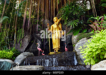 Goldene Buddha-Statue im tropischen Garten mit Wasserfall im Wat Saket goldenen Berg Tempel in Bangkok Stockfoto