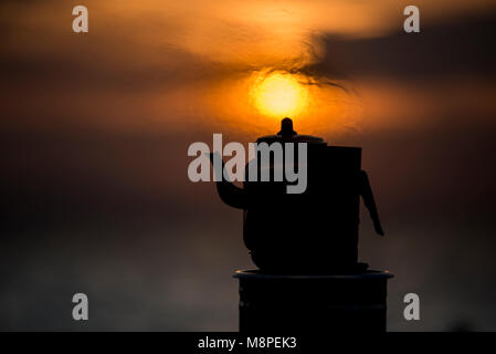 Silhouette Teekanne auf Sonnenuntergang mit heißem Dampf über Sie. Stockfoto