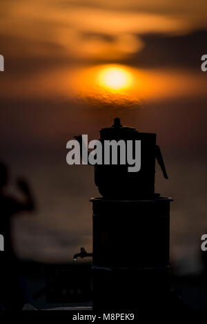 Silhouette Teekanne auf Sonnenuntergang mit heißem Dampf über Sie. Stockfoto