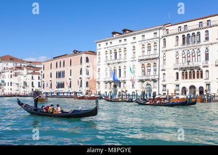 Touristen auf Gondeln auf dem Canal Grande, San Marco, Venedig, Venetien, Italien, Palazzo und Palazzo Manolesso Flangini Fini an einem sonnigen blauen Himmel gewinnen Stockfoto