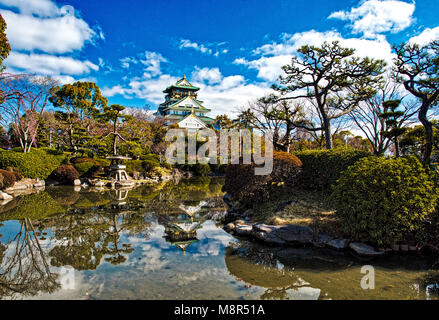 Burg von Osaka reflektiert in einem ruhigen Pool im frühen Frühling mit Kirschblüten und blauer Himmel Stockfoto