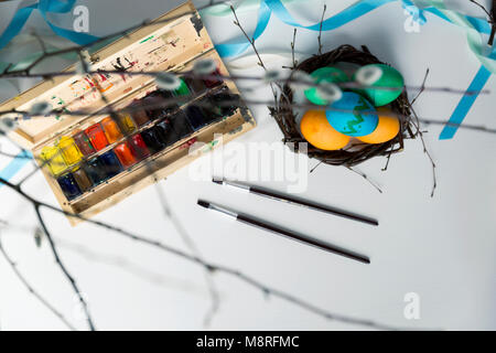 Ostern, Urlaub, Tradition und Personen Konzept - Ostereier färben mit Farben und Pinsel. Frohe Ostern Konzept Stockfoto