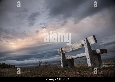 Lonely Sitzbank im Park mit bewölktem Himmel Stockfoto