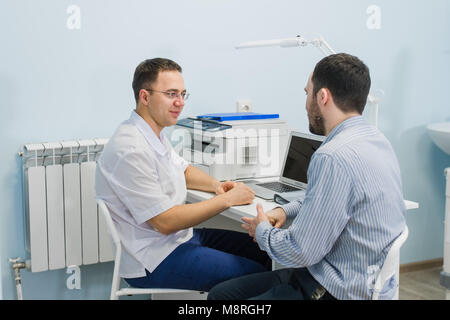Arzt lächelnd und im Gespräch mit Patienten im Büro Stockfoto