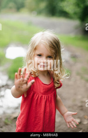 Lächelnd kleine blonde Mädchen spielen im Freien im Schlamm Stockfoto