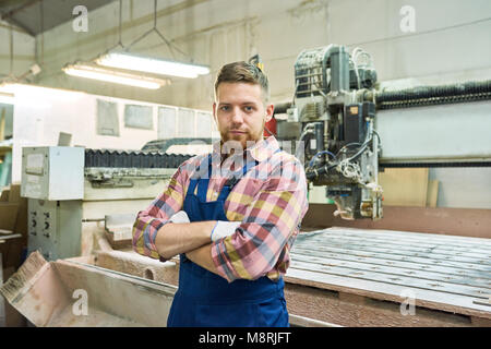 Junge Fabrikarbeiterin posiert in Werkstatt Stockfoto