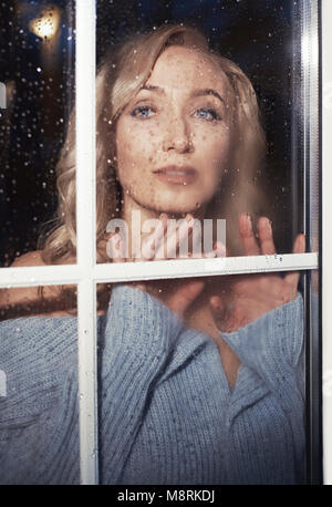 Portrait von selbstbewusste Frau durch nasses Fenster zu Hause gesehen Stockfoto