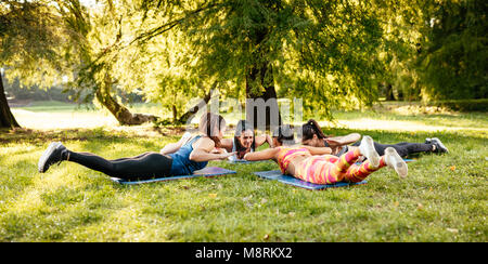 Vier schöne motivierte weibliche Freunde tun stretching Übung im City Park. Stockfoto