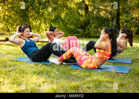 Vier schöne motivierte weibliche Freunde magen Übungen im City Park. Stockfoto
