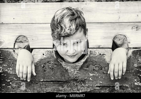 Jungen kaukasischen Jungen in mittelalterlichen Pranger. Elend Thema. Strafe Gerät. Schwarz-weiß Foto. Stockfoto