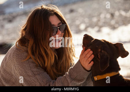 Glückliche Frau Streichelzoo Hund im Winter Stockfoto