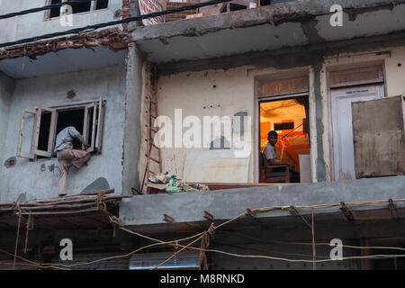 Neu Delhi, Indien: In einem Gebäude renoviert wird Sadar Bazar, ein Mann versucht, durch das Fenster zu, während ein anderer Werke in seinem Büro ein. Stockfoto