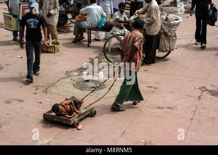 Neu Delhi, Indien: eine behinderte Person mit einem kleinen Rädern Plattform entlang der Straße der Meena Basar geschleppt, in der Nähe der Jama Masjid Moschee, Delhi. Stockfoto