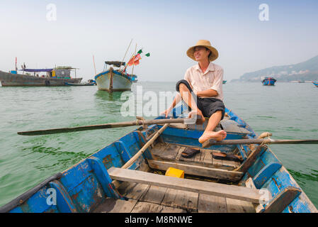 Vietnam Fischerboot, in Vung Tau Hafen ein Mann Zeilen sein Boot in die traditionelle Methode mit Hilfe seiner Füße, um seine Hände frei, um Fische zu halten. Stockfoto
