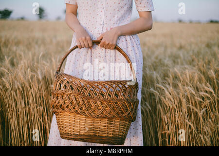 Mittelteil der Frau mit Weidenkorb beim stehen inmitten von Pflanzen Stockfoto