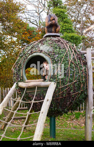 Ein junges Mädchen ihren Kopf aus einer Kokosnuss Klettergerüst Haus in einem Abenteuerspielplatz im Castlewellan County Down Nordirland knallen Stockfoto