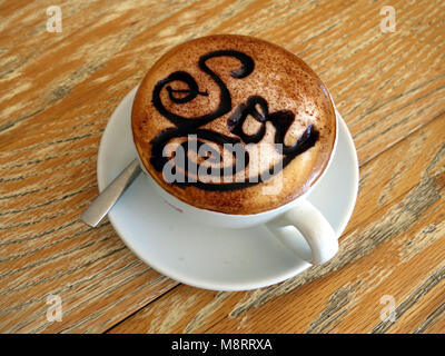 Ein Cappuccino mit Sojamilch in einer Schale, die eine Untertasse bereit für Trinkwasser gemacht Stockfoto