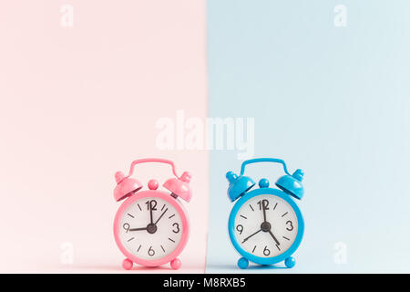 Zwei kleine Wecker auf Pastell blau und rosa Hintergrund. Arbeitszeit minimal Konzept. Stockfoto