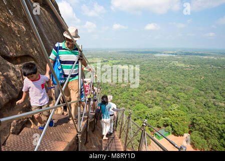 Ein Blick auf die Touristen klettern auf den Gipfel des Sigiriya Felsen, die Aussicht und wie steil an einem sonnigen Tag mit blauen Himmel. Stockfoto