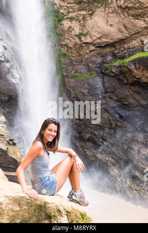 Mädchen sitzt neben Wasserfall in den Bergen von Rio de Janeiro, Brasilien Stockfoto