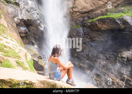 Mädchen sitzt neben Wasserfall in den Bergen von Rio de Janeiro, Brasilien Stockfoto