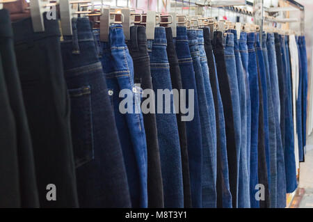 Jeans auf Kleiderbügeln sind in der modeboutique der Kleidung Markt verkauft. Stockfoto