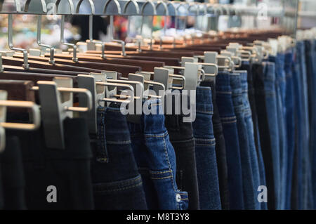 Jeans auf Kleiderbügeln sind in der modeboutique der Kleidung Markt verkauft. Stockfoto