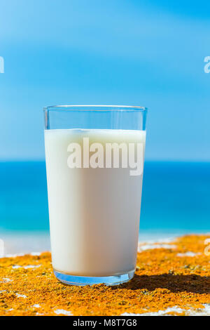 Glas gefüllt mit Kuhmilch blauen Himmel und Meer Stockfoto