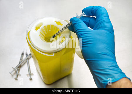 Montreal, Kanada 18, März 2018. behandschuhte Hand abfüllen eine gebrauchte Spritze in einem medizinischen Container. Credit: Mario Beauregard/Alamy leben Nachrichten Stockfoto