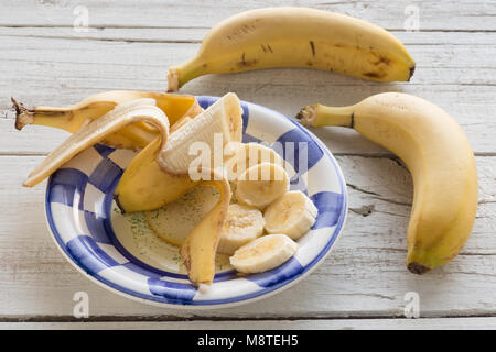 Eingestellt von Bananen in Scheiben geschnitten auf einer Platte auf weißem Holz- Hintergrund Stockfoto