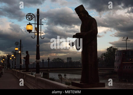 SKOPJE, MAZEDONIEN - Stadtzentrum mit Gehweg und eine Brücke über den Fluss Vardar bei Sonnenuntergang Stockfoto