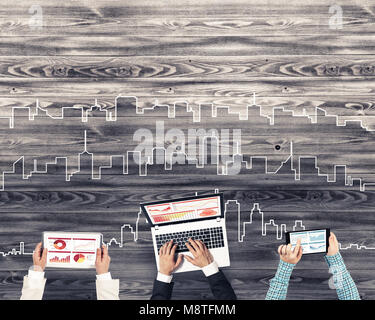 Gruppe von drei Personen mit Geräten in Händen arbeiten zusammen als Symbol der Vernetzung und Kommunikation Stockfoto