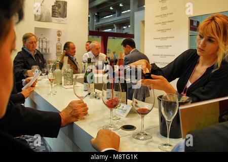 Blonde Frau gießen Rotwein aus der Flasche in das Glas des Kunden Stockfoto