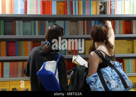 Frauen von hinten Kommissionierung Bücher aus den Regalen in einer Buchmesse Turin Italien ca. Mai 2015 Stockfoto