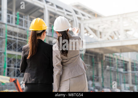 Auf der Rückseite. Eine Ingenieurin, die ein Bauvorhaben, für das eine andere Frau Architekt auf einer Baustelle. Angezeigte Konzept. Stockfoto