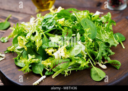 Frische Blätter von gemischter Salat auf einem hölzernen Hintergrund. Stockfoto