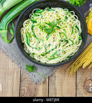 Nudeln mit Zucchini auf dunklem Hintergrund in einer gusseisernen Pfanne. Spaghetti aus bio Vollkornmehl. Stockfoto