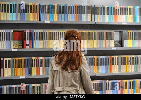 Frau roten Haaren zurück Vor der Bücherwand Turin Italien ca. Mai 2016 Stockfoto