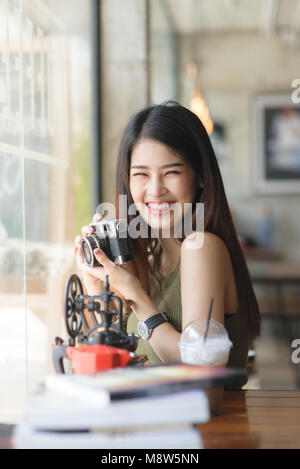 Gerne asiatische Frau mit Vintage Kamera im Cafe, Lifestyle Konzept. Stockfoto