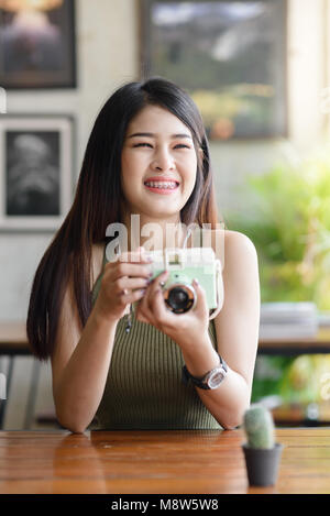 Gerne asiatische Frau unter Foto Kaktus von Vintage Kamera im Cafe, Lifestyle Konzept Stockfoto