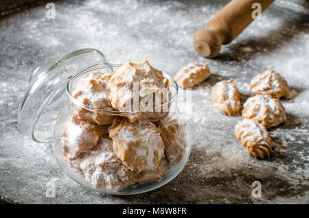 Gezuckerte Plätzchen mit Puderzucker in die Glasschale und Dough roller. Pulverförmige Dark Metal Hintergrund Stockfoto